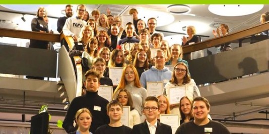 Junge Menschen stehen auf einer Treppe und halten Urkunden vor sich