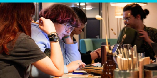 Vier junge Menschen arbeiten konzentriert am Laptop.