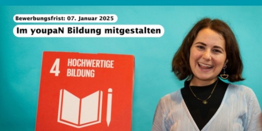 Eine junge Person lacht in die Kamera. Sie steht vor blauem Hintergrund und hält einen roten Würfel hoch, auf dem in weißer Schrift "Hochwertige Bildung" steht.