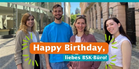 Vier Menschen, unser BSK-Büro-Team, schauen in die Kamera. Dazu die Aufschrift: „Happy Birthday, liebes BSK-Büro!“