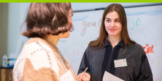 Zwei junge Frauen blicken sich gegenseitig ins Gesicht. Eine davon ist nur im Profil zu sehen.