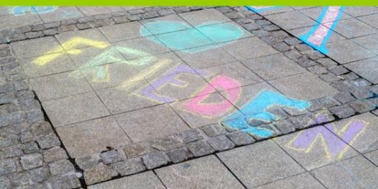 Auf Pflastersteinen ist mit bunter Kreide das Wort "Frieden" geschrieben, zusammen mit einem Herz