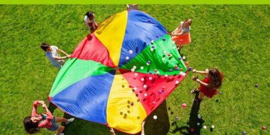 Kinder spielen mit einem bunten Schwungtuch. Man sieht sie aus der Vogelperspektive.