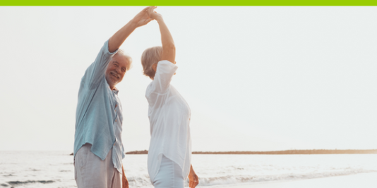 2 ältere Menschen tanzen glücklich am Strand