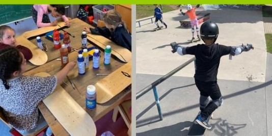 Kinder bemalen an einem Tisch Skateboards mit Farbe, ein anderes Kind fährt auf einem Skateboard eine Rampe herunter