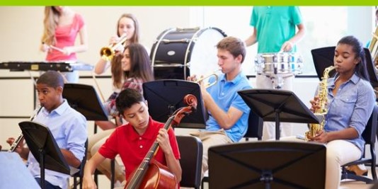 Junge Menschen sitzen auf Stühlen und spielen Instrumente wie eine Trompete, Cello oder Saxophon. Vor ihnen stehen Notenständer.