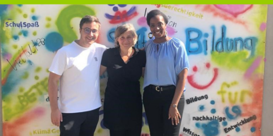 Oliver Sachsze, Katja Hintze, Elisabeth Kaneza stehen zusammen vor einer bunt angemalten Wand der Stiftung Bildung