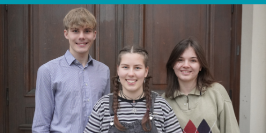 Von links nach rechts: Erik Sczygiol, Amy Kirchhoff und Lilli Berthold stehen nebeneinander und lächeln in die Kamera.