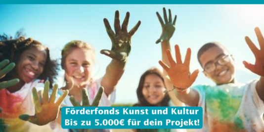 4 Kinder schauen glücklich in die Kamera, sie zeigen ihre Hände, die voller Farbe sind. Auch ihre T-Shirts sind voll mit Farbe.