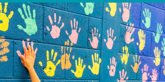 Bunte Handabdrücke auf einer blauen Wand.