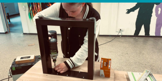 ein junger Mensch arbeitet mit einem Akkuschrauber an einem Möbelstück