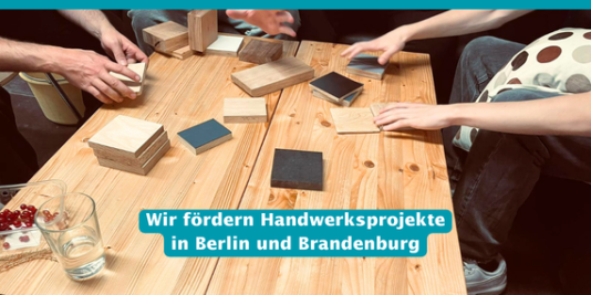 Mehrere Menschen sitzen an einem Tisch und arbeiten mit Holz. Dazu der Text: Wir fördern Handwerksprojekte in Berlin und Brandenburg