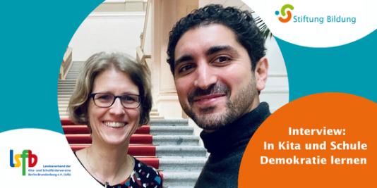 2 Menschen lächeln auf einem Selfie in die Kamera. Im Hintergrund ist eine Treppe zu sehen.