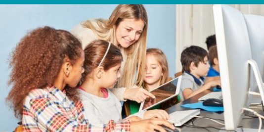 Gruppenbild von Kindern an Bildschirmen mit einer Lehrkraft