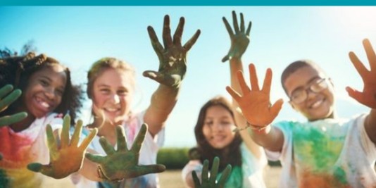 Kinder lachen in die Kamera und haben bunte Farbe an den Händen.