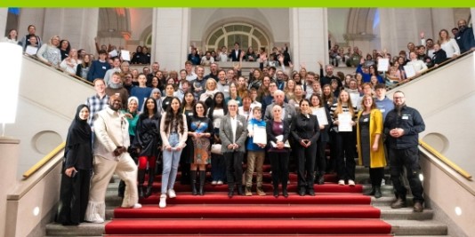 Viele Menschen stehen zum Gruppenbild auf einer großen Treppe mit rotem Teppich.