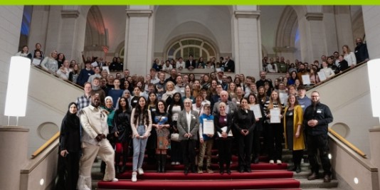 Viele Menschen stehen zum Gruppenbild auf einer großen Treppe mit rotem Teppich.